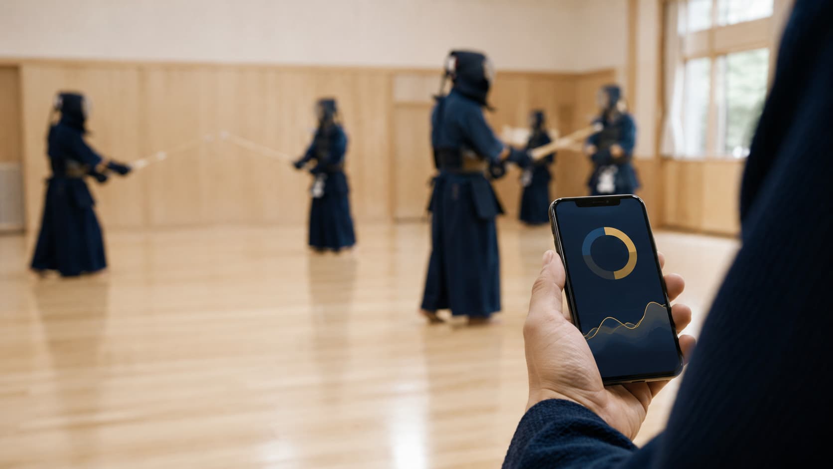 道場でスマートフォンの剣道スコアブックアプリを開き、団体戦の戦績をグラフで確認する様子